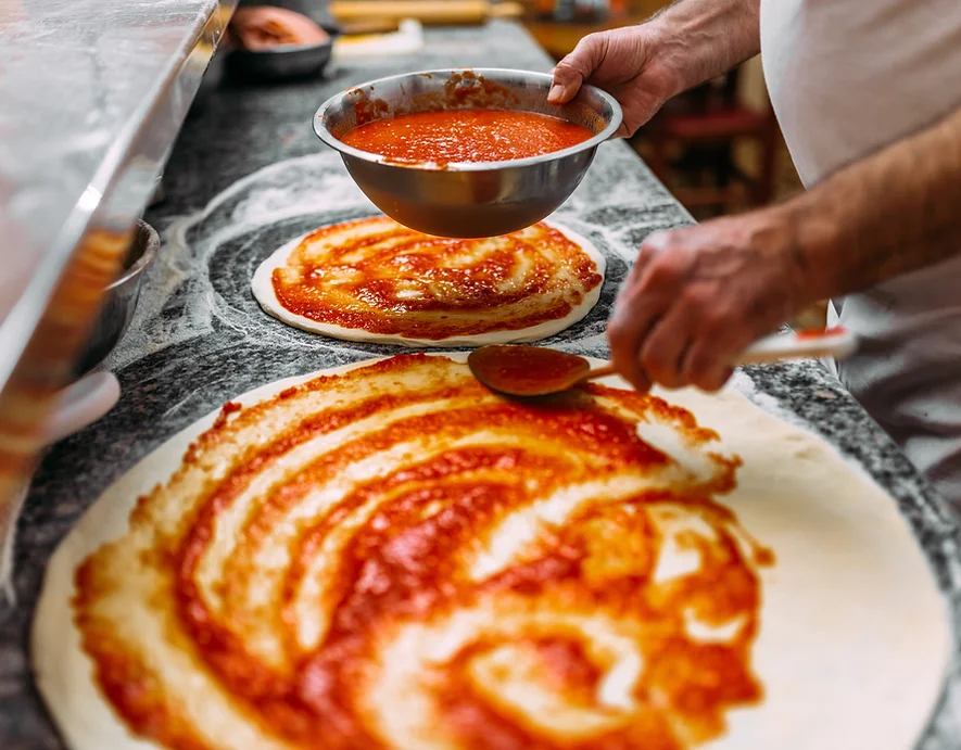 photo du chef de la pizzéria réalisant 2 magnifiques pizzas